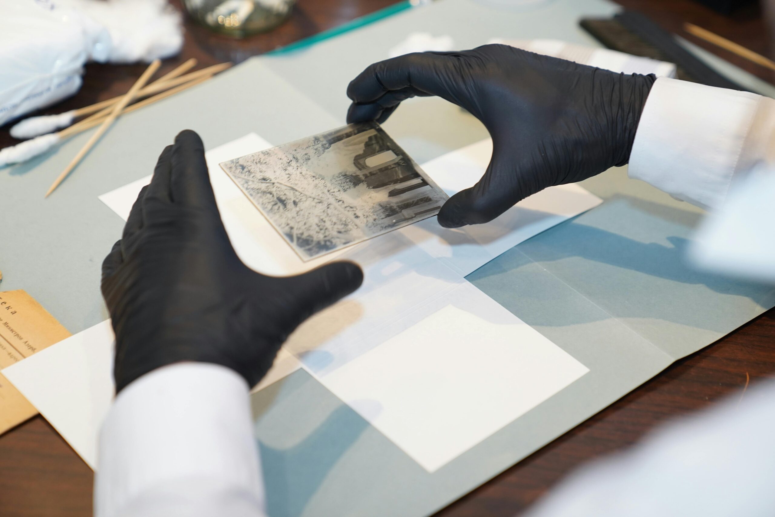 Inicio A specialist restoring an old photo using gloves and tools for careful preservation.